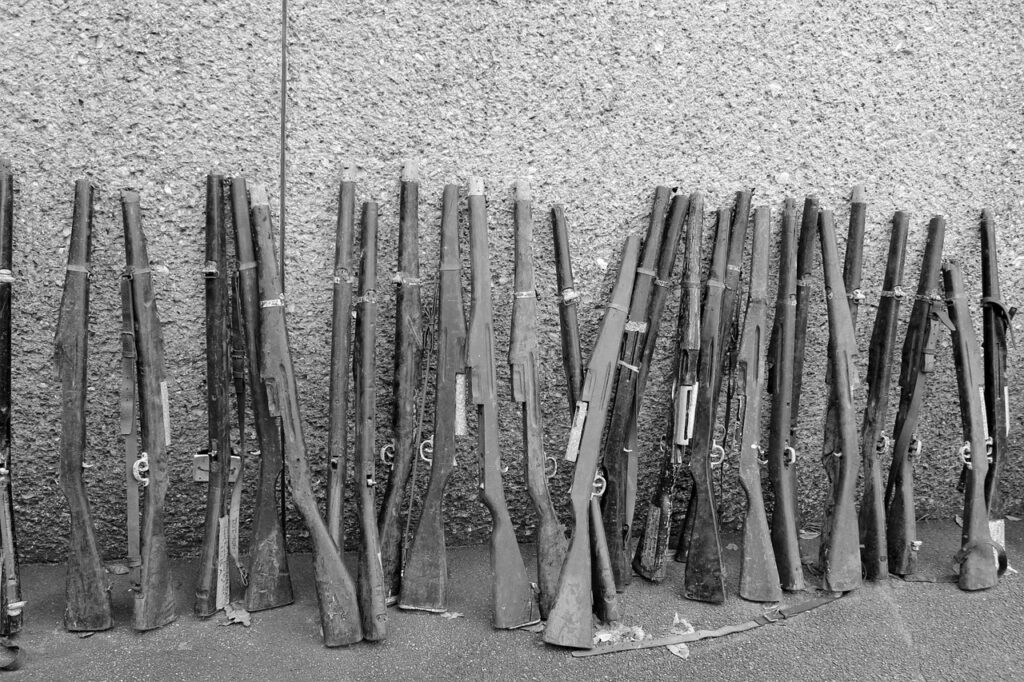 many rifles and shotguns leaning against a wall